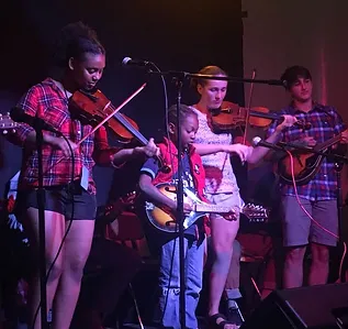 four students playing music on stage