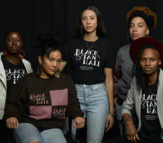 five black women wearing black and tan t-shirts