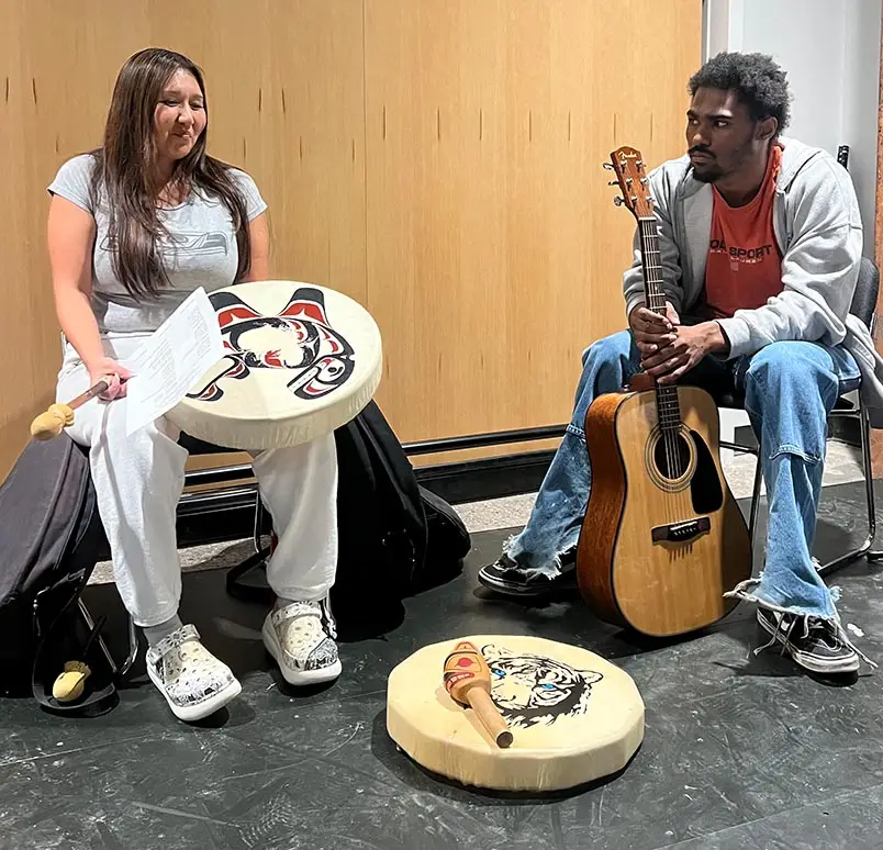 man and woman in diy program with drums and acoustic guitar