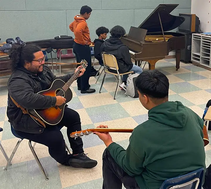 jed playing guitar and music with students in classroom