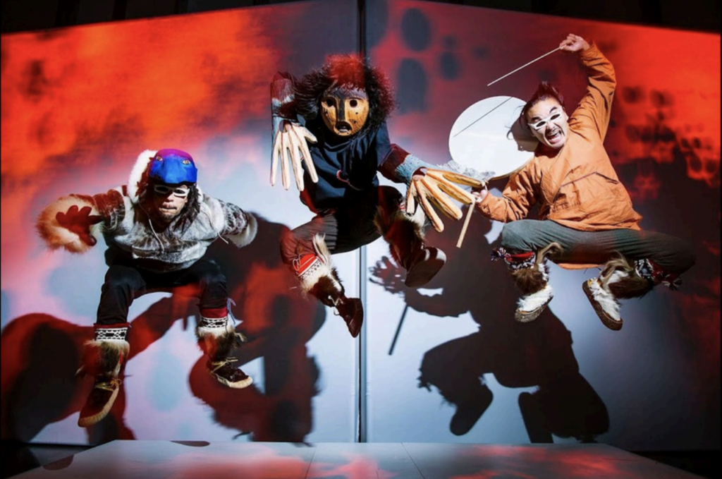 Photo of Payma! Intuit-Soul musical Group jumping in front of a red and white and black lit background